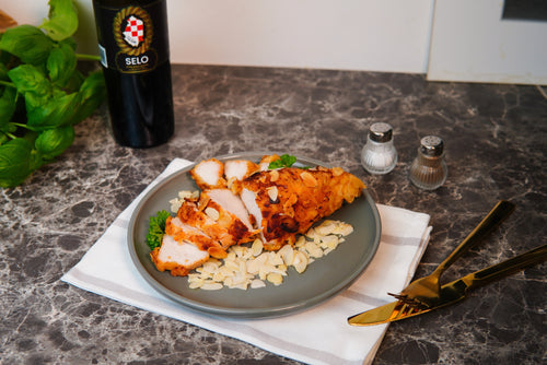 Almond-crusted turkey breast cooked in Croatian olive oil on a serving plate, garnished with fresh herbs